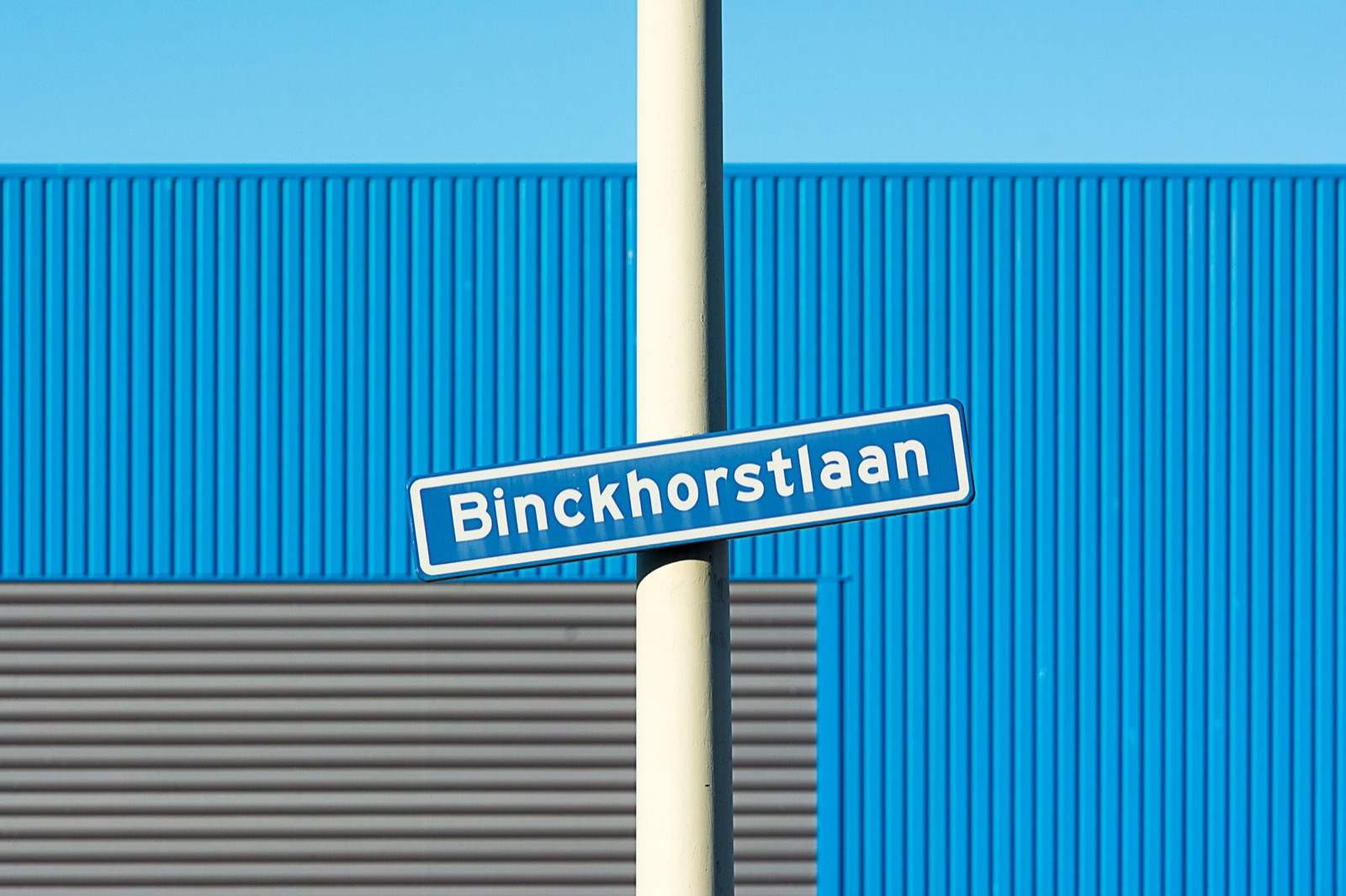 Straatnaambord van de Binckhorstlaan voor een blauwe bedrijfshal op een bedrijventerrein