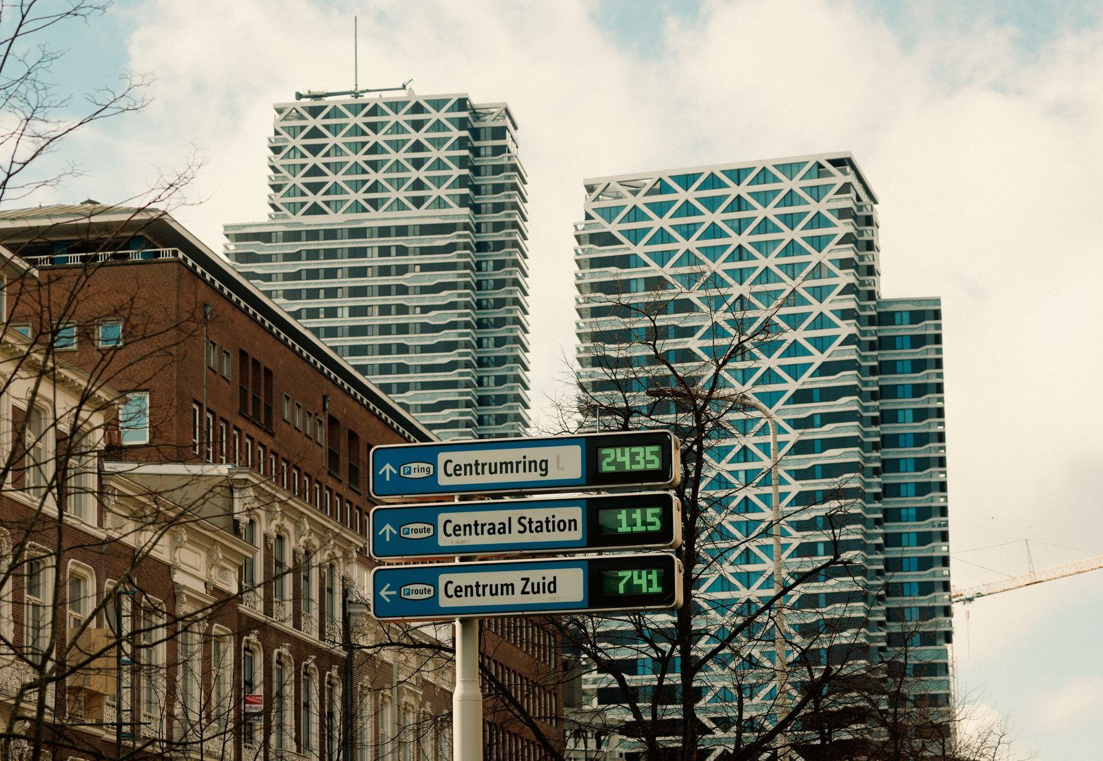 Twee hoge woontorens in Den Haag achter bewegwijzering met het aantal vrije parkeerplaatsen