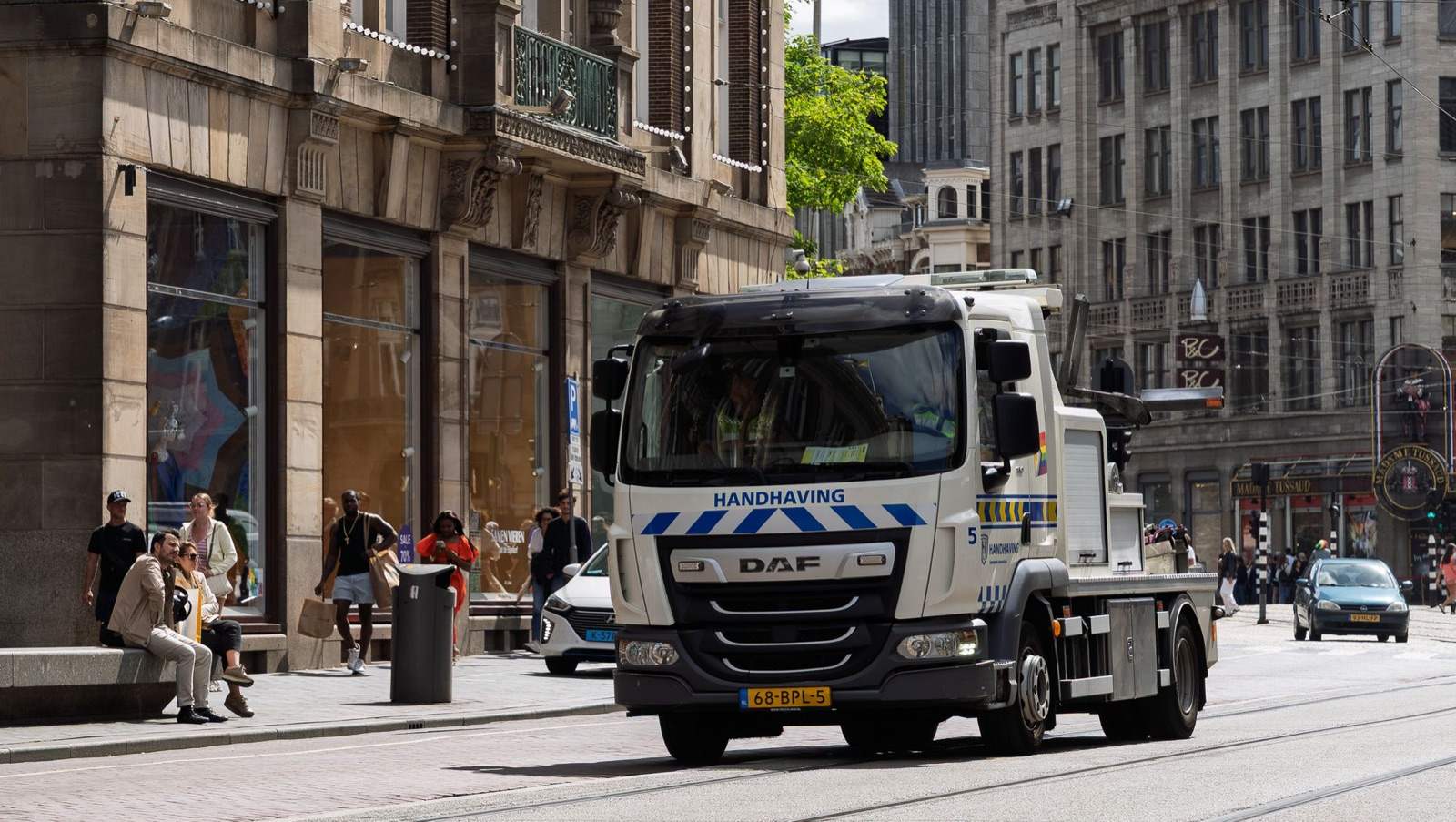 Een takelwagen van Handhaving rijdt door een drukke straat in Amsterdam
