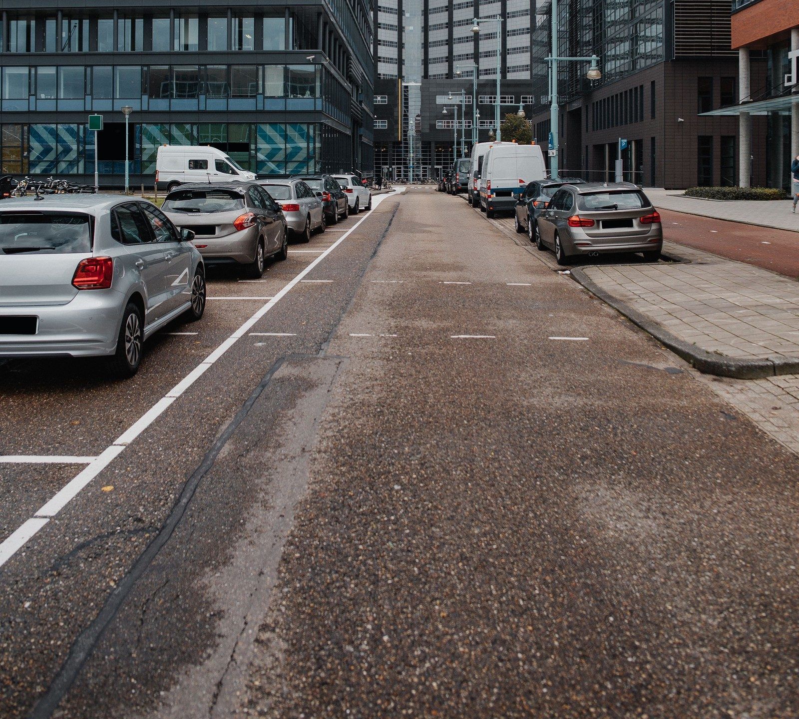 Straat met geparkeerde auto's in parkeervakken tussen kantoorgebouwen