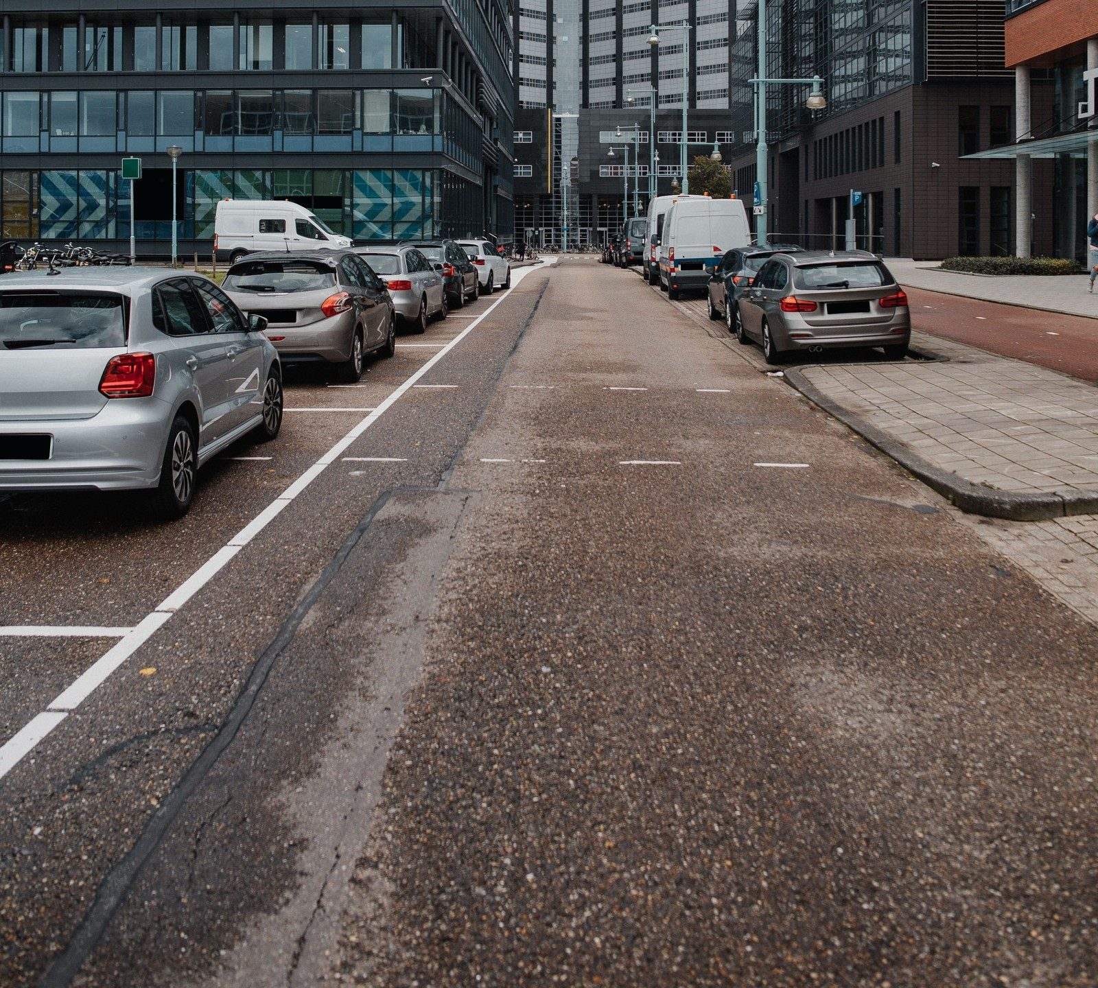 Straat met geparkeerde auto's in parkeervakken tussen kantoorgebouwen