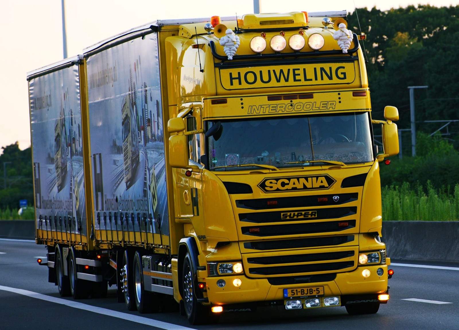 Een gele Scania-vrachtwagen met aanhanger op een Nederlandse snelweg